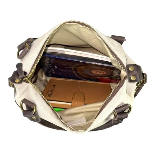 Draufsicht auf eine gefüllte Canvas-Reisetasche mit Schultergurt und festen braunen Ledergriffen für alle Reisen.